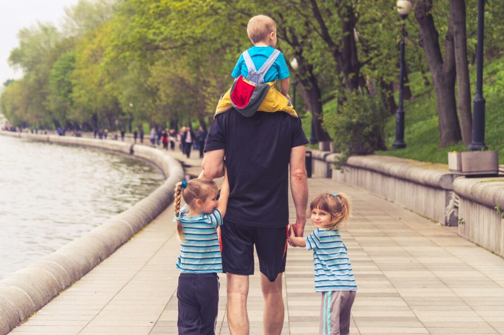 Father walking with his three children at a park. 
