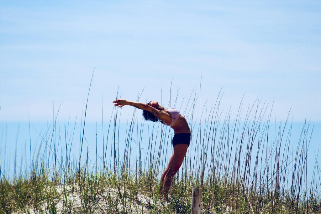 Woman doing long yoga stretch on the beach.
