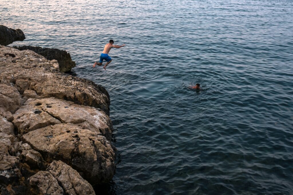 Boys jumping off cliff rocks in Newport, Rhode Island. 