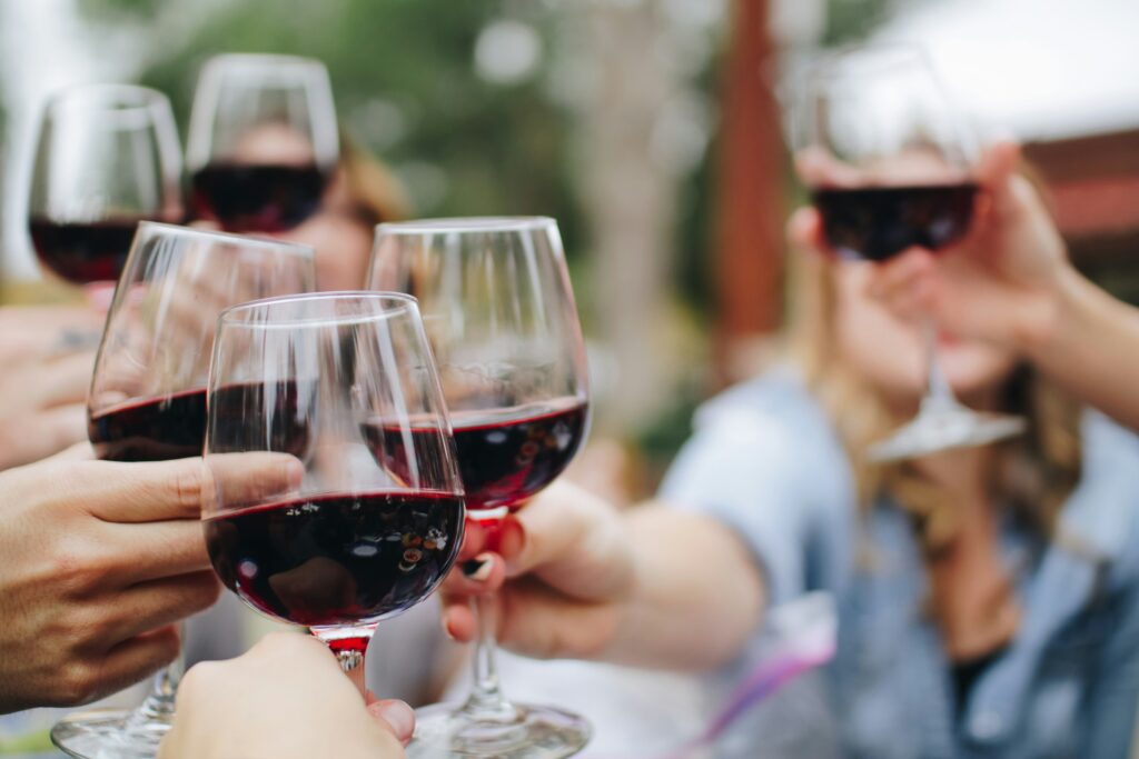 A group of hands holding full wine glasses full of red wine toasting together at a Rhode Island winery. 