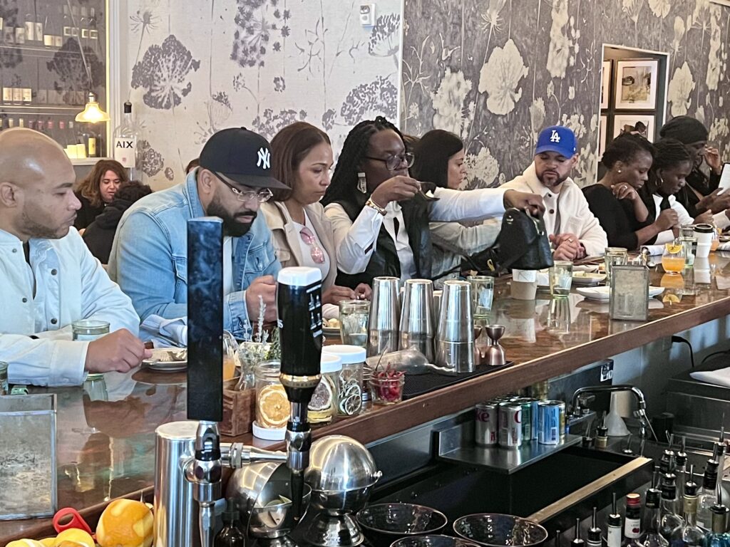 A group is seated at a bar in Newport, Rhode Island, sharing dishes and enjoying drinks on a food tour. 