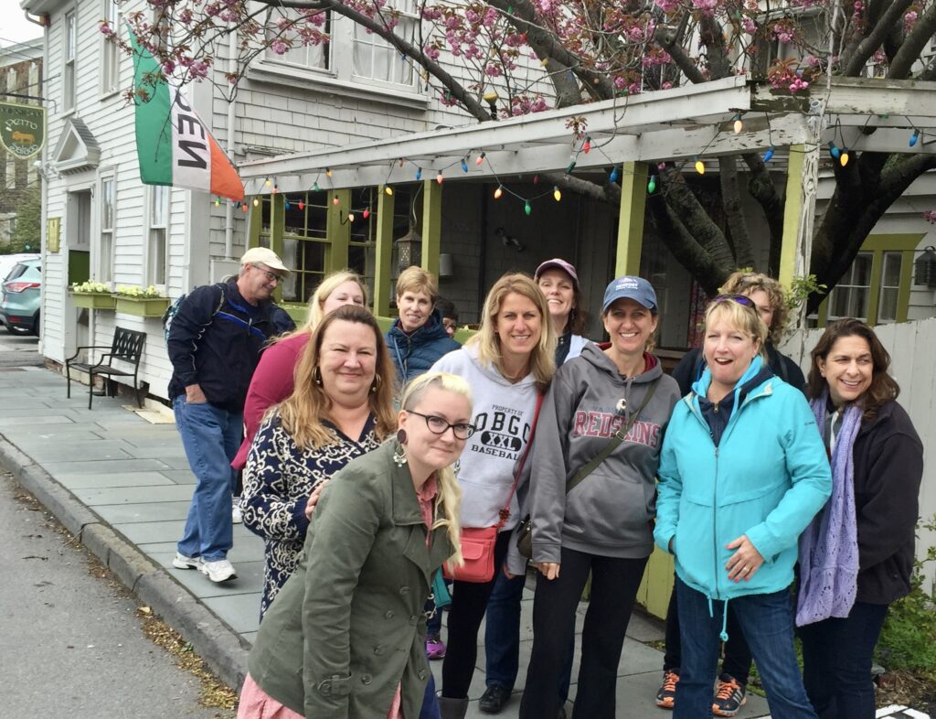 A group on a food tour in Newport, Rhode Island, smile in front of a Mexican restaurant called Perro Salado.  